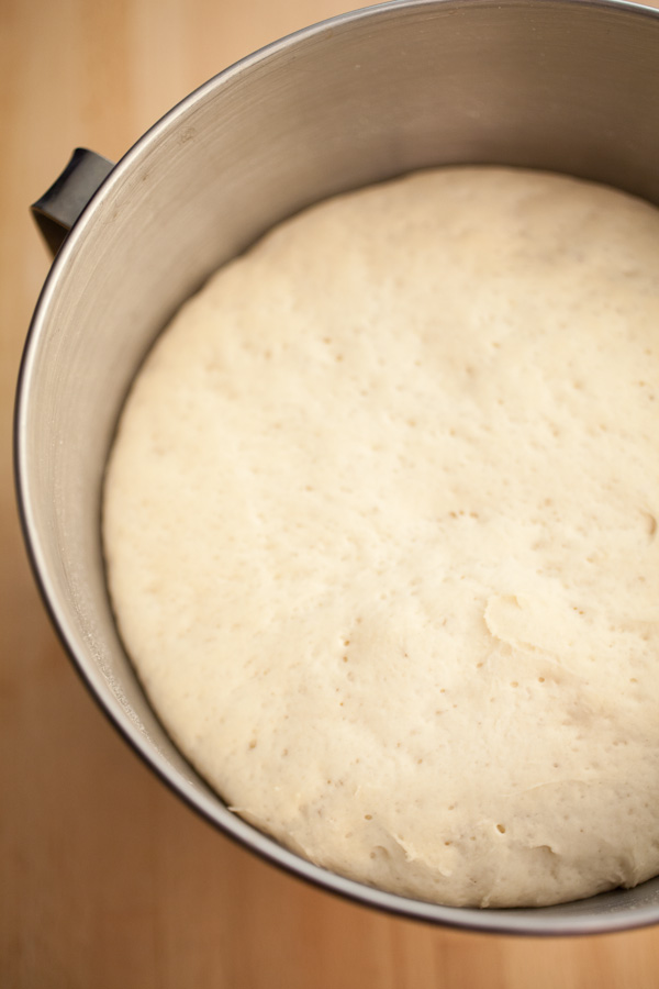 Pizza dough risen in metal bowl.