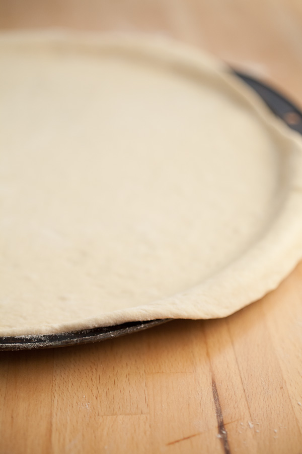 Rolled out pizza dough on metal pizza pan.