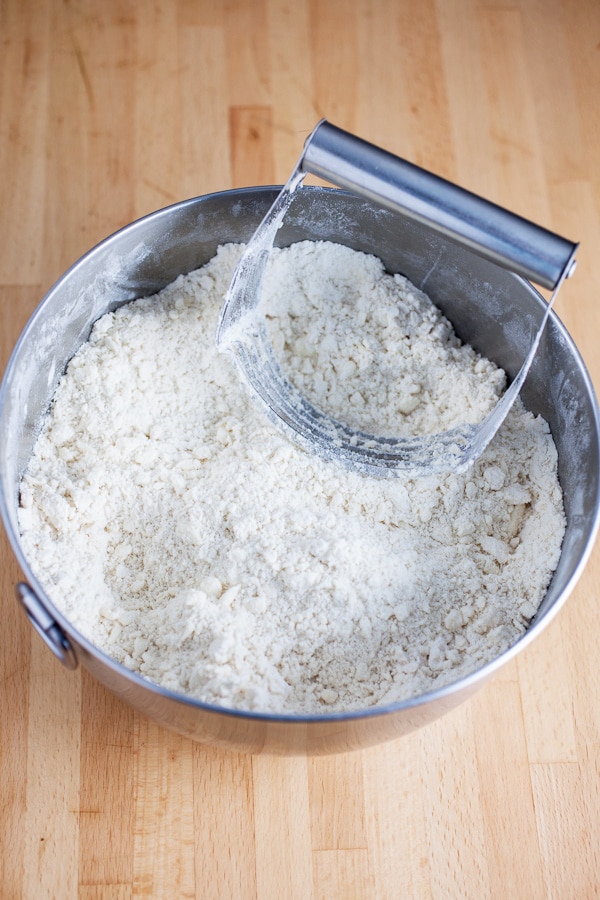 Flour and butter cut together in metal bowl with pastry cutter.