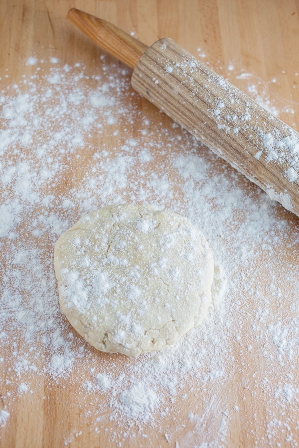 Round of pie dough with wooden rolling pin.