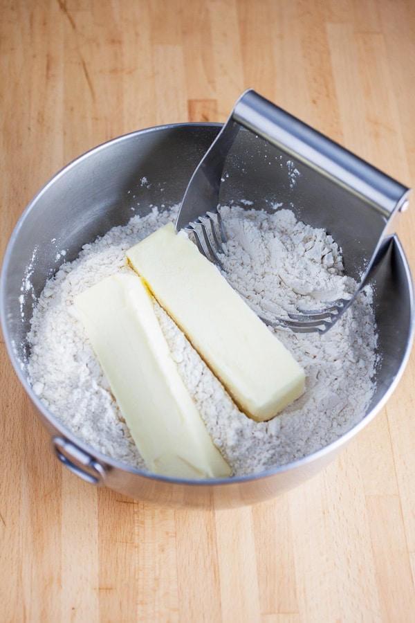 Flour and butter in metal bowl with pastry cutter.