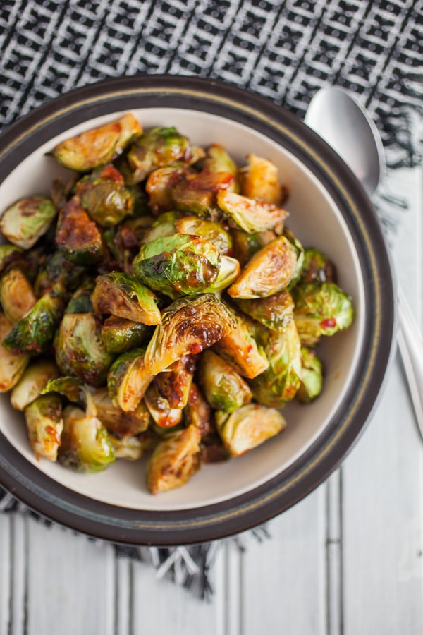 Sweet spicy roasted Brussels sprouts in bowl with spoon.