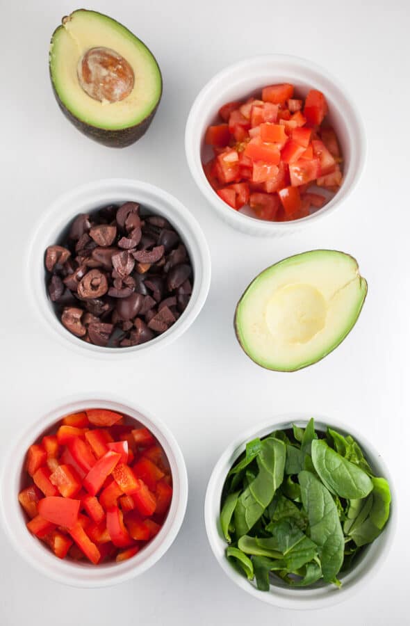 These Mediterranean Salmon and Farro Buddha Bowls are quick, easy, and healthy! Salmon is simple and fast to cook on the stove top. This fresh bowl has farro and vegetables like kalamata olives, red peppers, tomatoes, and avocados. This salad bowl makes a great lunch or dinner recipe. I love recipes like this that only take 20 minutes! #mediterranean #salmon #farro #bowl #salad #kalamataolives chopped red pepper, spinach, kalamata olives, avocado, and tomato