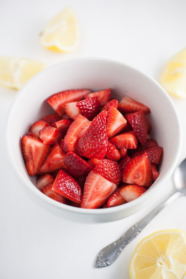 Chopped fresh strawberries with lemon juice in small white bowl.