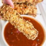 Eggplant Parmesan fry dipped into small bowl of marinara sauce.