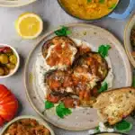 Borani banjan vegan Afghan eggplant on plate garnished with fresh herbs and slice of bread.