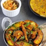 Brinjal fry in serving dish garnished with fresh cilantro.