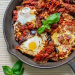 Eggplant shakshuka in skillet garnished with basil.