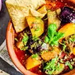 Vanji batata bhaji eggplant potato curry in bowl garnished with fresh herbs and flatbread.