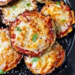 Eggplant Parmesan on plate garnished with fresh basil.