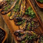 Miso eggplant on wooden serving board garnished with scallions.