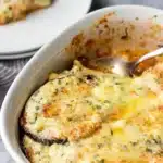 Eggplant gratin in baking dish with metal serving spoon.