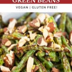 Garlic roasted green beans with toasted almonds and lemon zest in white bowl.