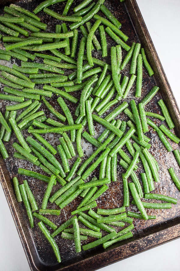 Uncooked green beans on metal baking sheet.