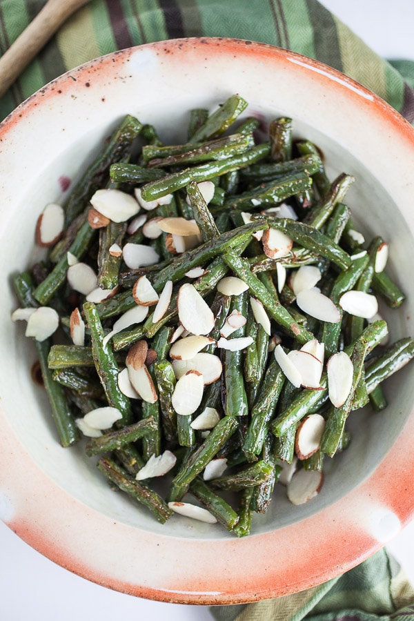 Garlic roasted green beans with almonds in ceramic bowl.