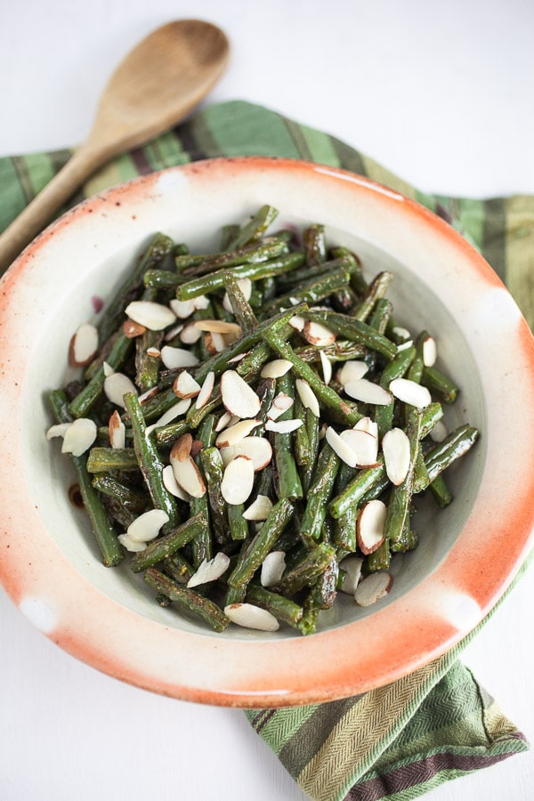 Roasted green beans with almonds in ceramic bowl.