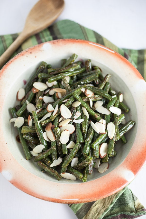 Garlic roasted green beans with almonds in ceramic bowls.