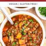 Hearty lentil soup in white bowl with spoon.
