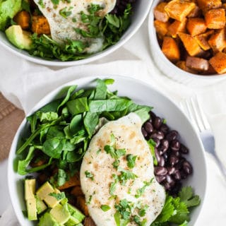 Sweet potato breakfast bowls with black beans, spinach, avocado, and eggs in white bowls.