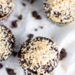 Coconut chocolate chip cupcakes with toasted coconut on white towel.