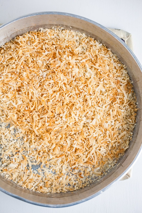 Toasted coconut in round metal cake pan.