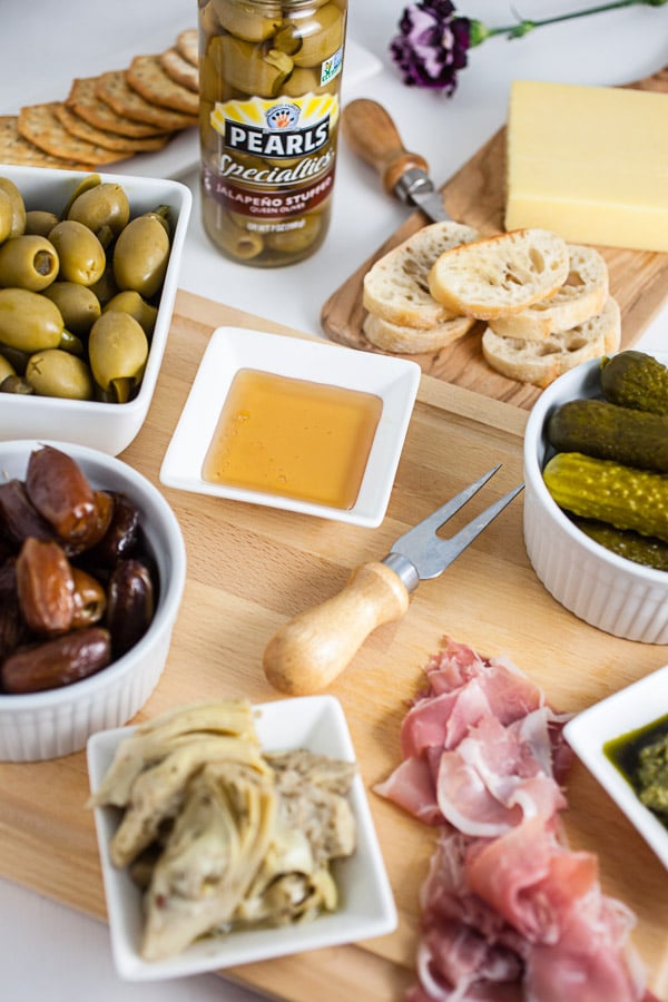 #AD This Simple Spring Antipasto Platter is so easy to assemble and is perfect for spring entertaining! The Italian antipasto platter is a recipe that's full of snacks and appetizers for a crowd. It's great for a party, holidays like Easter, weddings, bridal and baby showers, and graduations. Learn how to make a rustic antipasto platter with meat, cheese, artichokes, olives, and veggies for your next get-together. @PearlsOlives #OlivePearlsEaster #antipasto #easter #appetizer #Italian Simple Spring Antipasto Platter