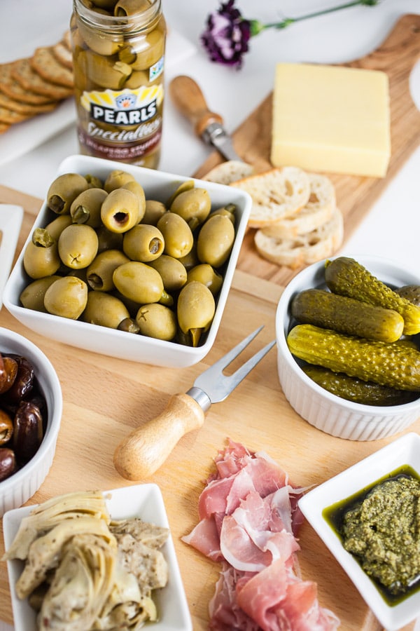 #AD This Simple Spring Antipasto Platter is so easy to assemble and is perfect for spring entertaining! The Italian antipasto platter is a recipe that's full of snacks and appetizers for a crowd. It's great for a party, holidays like Easter, weddings, bridal and baby showers, and graduations. Learn how to make a rustic antipasto platter with meat, cheese, artichokes, olives, and veggies for your next get-together. @PearlsOlives #OlivePearlsEaster #antipasto #easter #appetizer #Italian Simple Spring Antipasto Platter