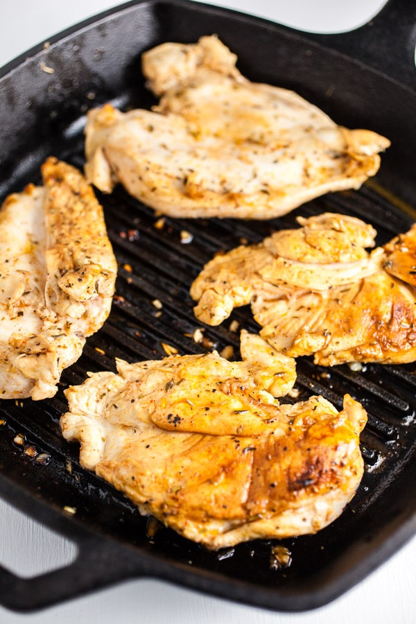 Chicken breasts cooking on cast iron grill pan.