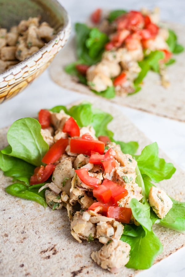 Tarragon chicken salad in wraps with lettuce and diced tomatoes.