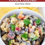 Southwest black bean corn salad garnished with cilantro in white bowl on platter with tortilla chips.