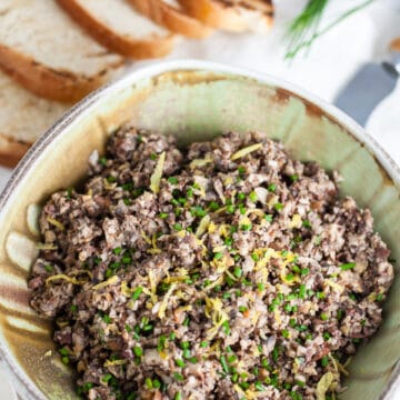 Roasted tapenade in ceramic bowl with grilled crostini.