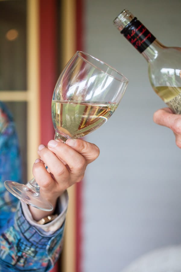 White wine poured into wine glass held by woman's hand.