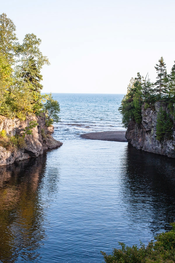 River running into Lake Superior in between rocky cliffs.