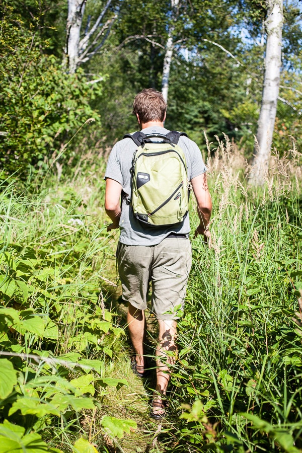 Man with backpack walking through path in woods.