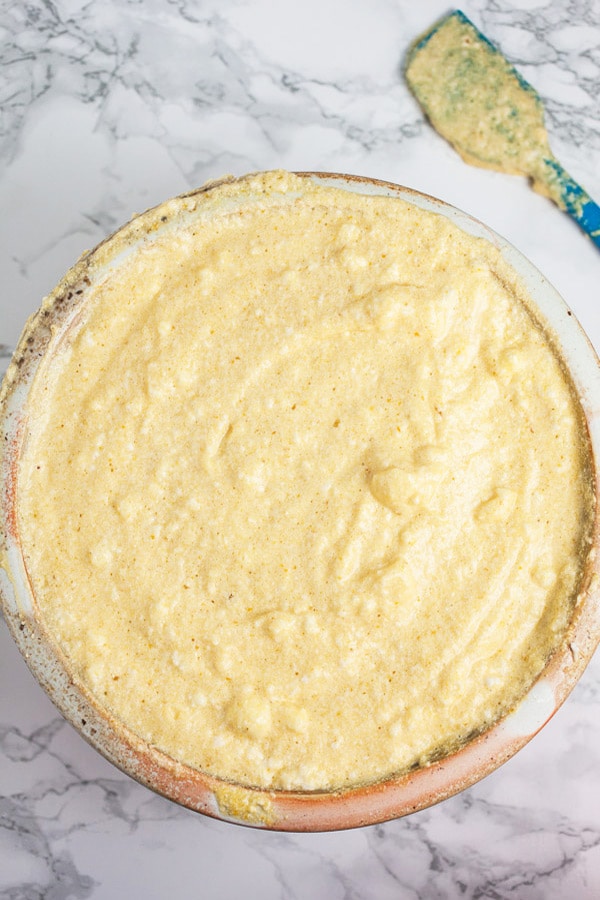 Pumpkin cheesecake batter in ceramic bowl next to blue spatula.