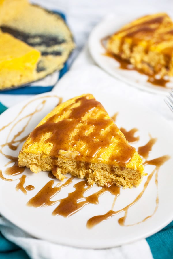 This Pumpkin Cheesecake with Cinnamon Caramel Sauce tastes like pumpkin pie but is much easier to make! This homemade cheesecake is the perfect recipe for easy fall baking! It's crustless, light, and creamy. A cinnamon caramel sauce topping is made from scratch and drizzled over the top. This is one of the best simple desserts for fall and Thanksgiving! #cheesecake #pumpkin #cinnamon #caramel #sauce #fall #thanksgiving Slices of crustless pumpkin cheesecake with caramel sauce on white plates.