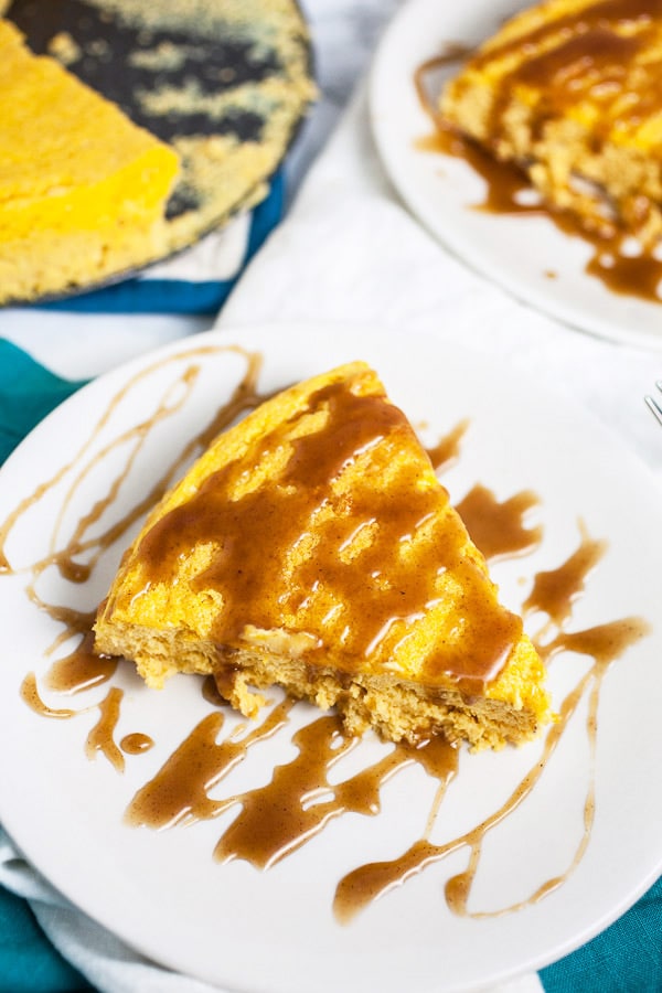 Slices of pumpkin cheesecake with caramel sauce on white plates.