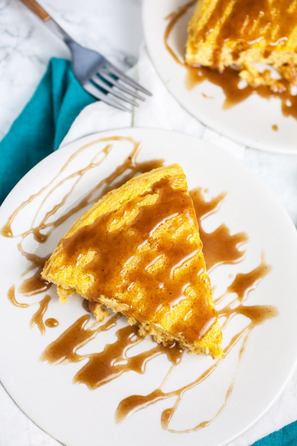 Slices of pumpkin cheesecake with caramel sauce on white plates.