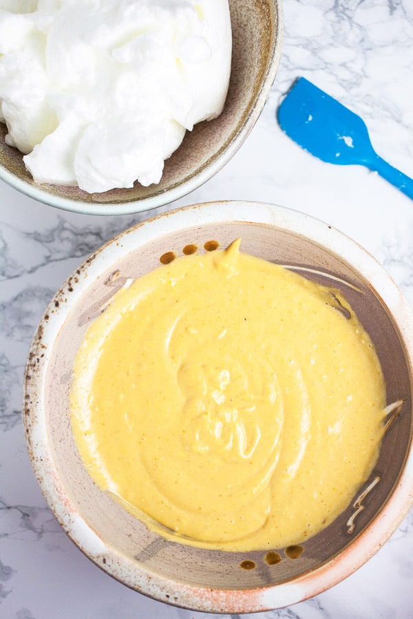 This Pumpkin Cheesecake with Cinnamon Caramel Sauce tastes like pumpkin pie but is much easier to make! This homemade cheesecake is the perfect recipe for easy fall baking! It's crustless, light, and creamy. A cinnamon caramel sauce topping is made from scratch and drizzled over the top. This is one of the best simple desserts for fall and Thanksgiving! #cheesecake #pumpkin #cinnamon #caramel #sauce #fall #thanksgiving Pumpkin cheesecake batter and meringue in two separate ceramic bowls.