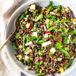 Italian wild rice salad in white serving bowl with spoon.