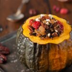 Wild rice, cranberries, pecans, and feta stuffed acorn squash on plate.