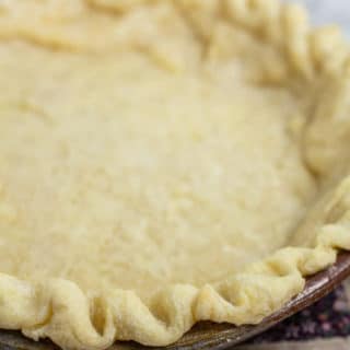 Parbaked pie crust in ceramic pie dish.