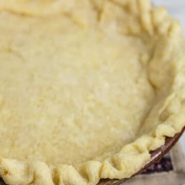 Parbaked gluten free pie crust in ceramic pie dish.