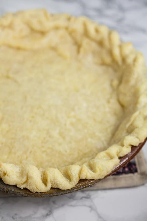 Parbaked gluten free pie crust in ceramic pie dish.