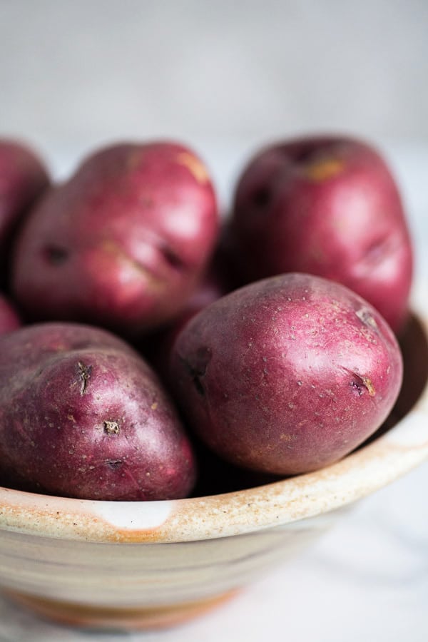 Whole red potatoes in ceramic bowl.