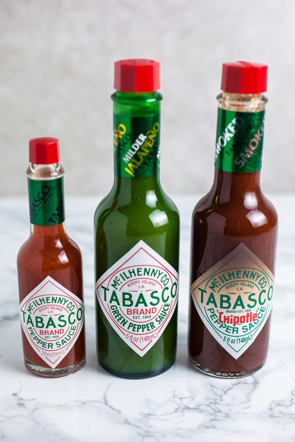 Three varieties of Tabasco sauce on white surface.