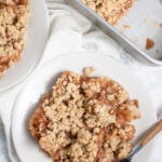 Gluten free apple crisp on small white plate with fork.
