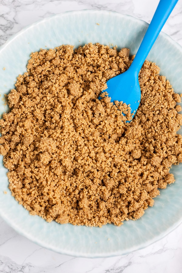 Graham cracker crust in blue bowl with spatula.