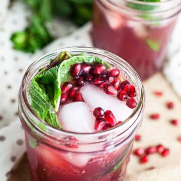 Pomegranate mojitos in mason jars with fresh mint.