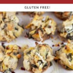 Spinach artichoke stuffed mushrooms on white serving platter.